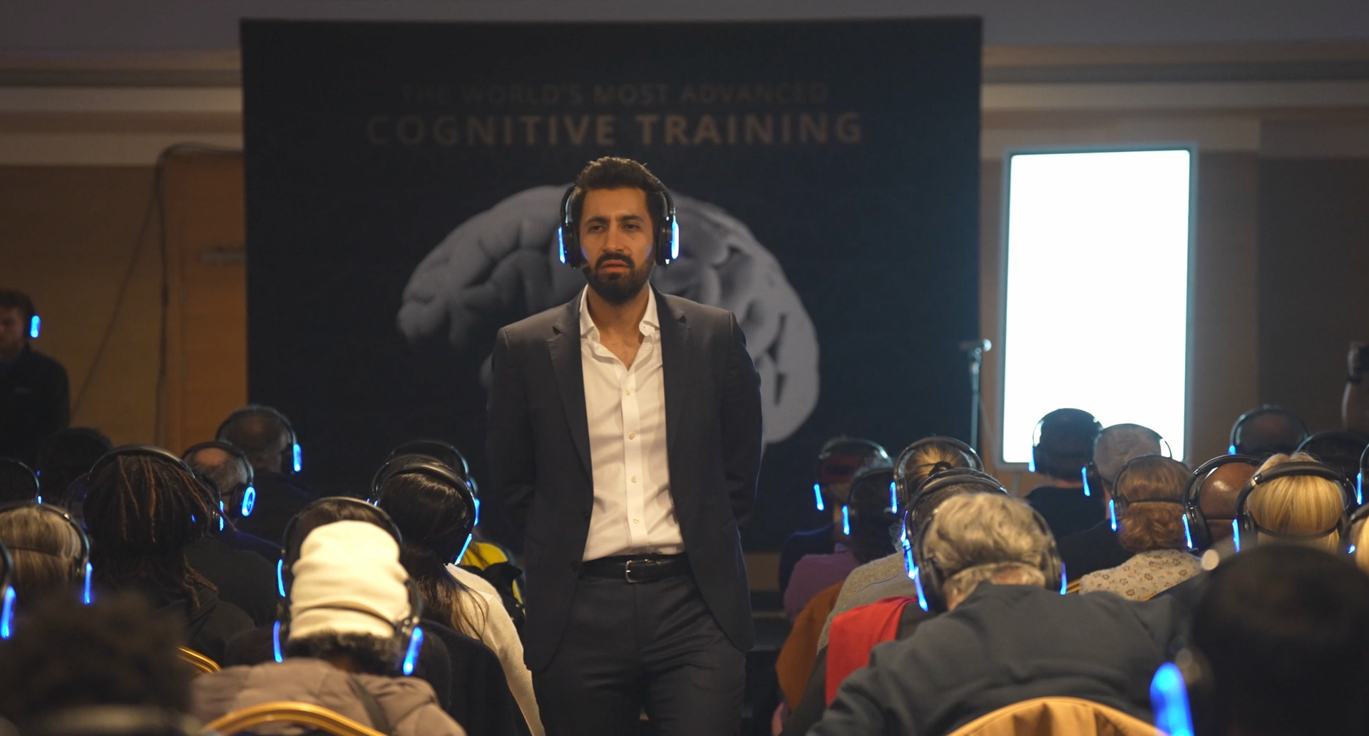 Yousuf Aslam delivering an immersive cognitive training session to a live audience wearing headphones